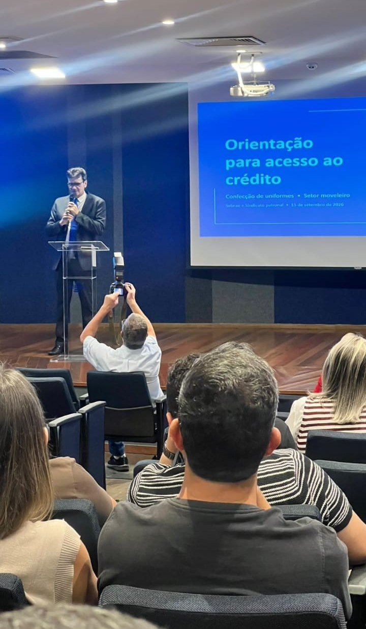 José Antonio Bastos no palco, ao lado do telão com o título Orientação para acesso ao crédito